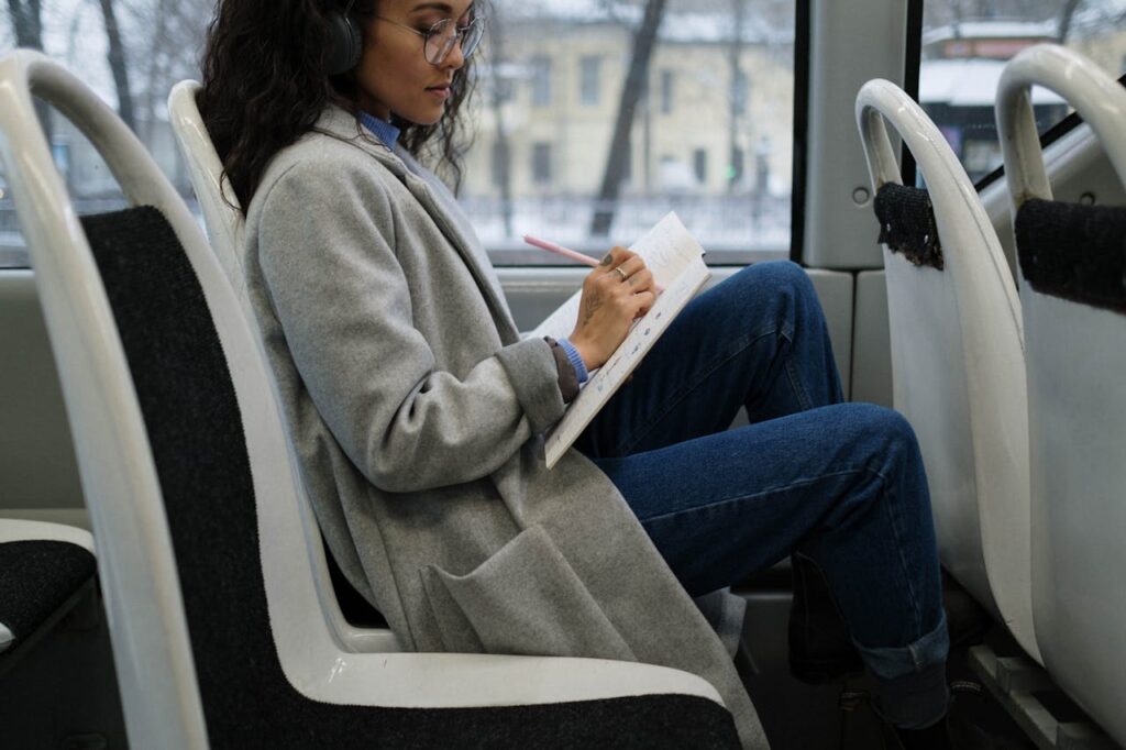 mujer escribiendo mientras va en autobús, aprovechando los ratos libres para escribir.