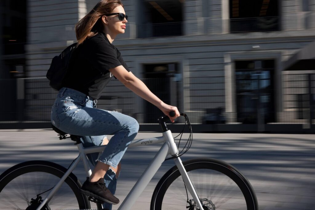 Mujer montando bicicleta mientras avanza por una ciudad.